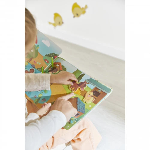 Child hands placing horse cutout on Janod Farm Busy Book activity page