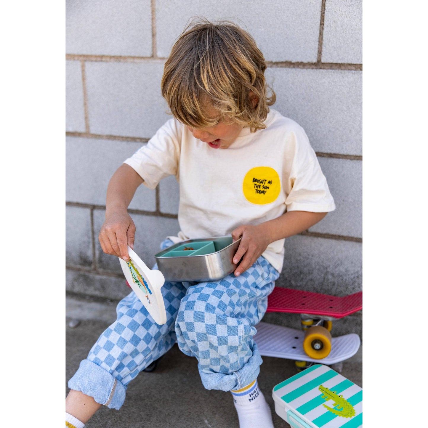 Child opening green silicone insert lunchbox with giraffe lid