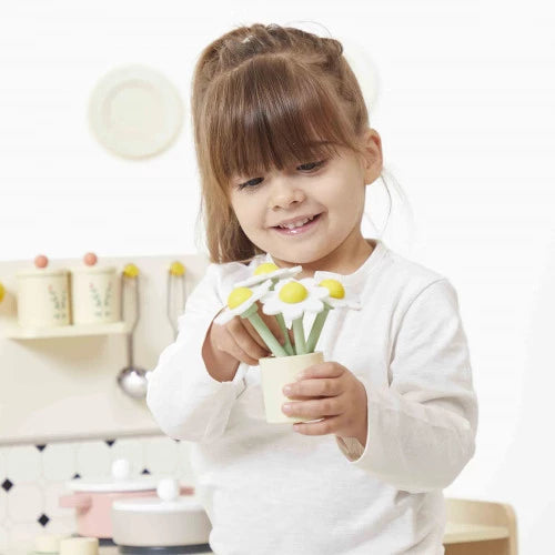 Child playing with Mamie Soleil wooden kitchen holding daisy cup