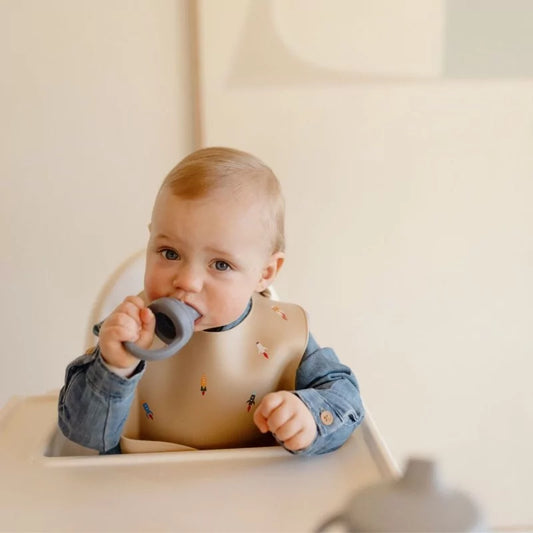 Baby chewing on grey silicone mushie feeder