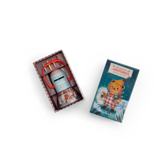 Open Moulin Roty packaging showing light blue lantern with pink dome, red handle, and stacked image discs