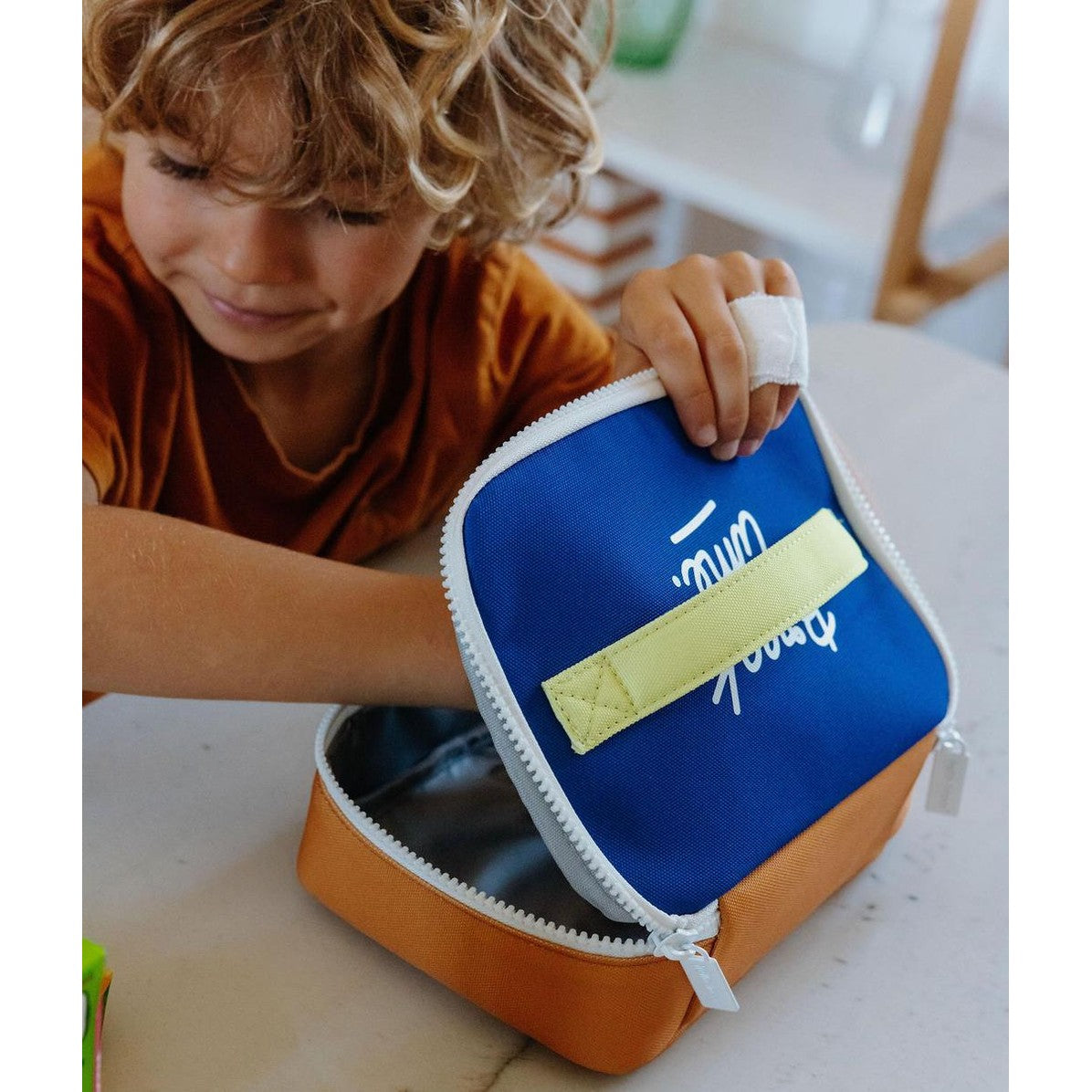 Child showing interior of blue and orange insulated lunch bag