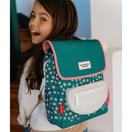 Girl smiling while wearing green floral square backpack with Hello Hossy tag