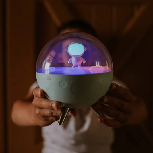 Person holding glowing blue moon night light in dim room