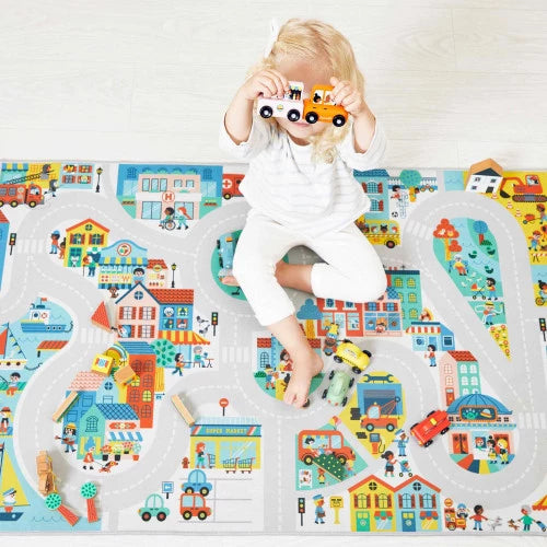 Toddler playing with orange wooden pull-along car on illustrated town play mat