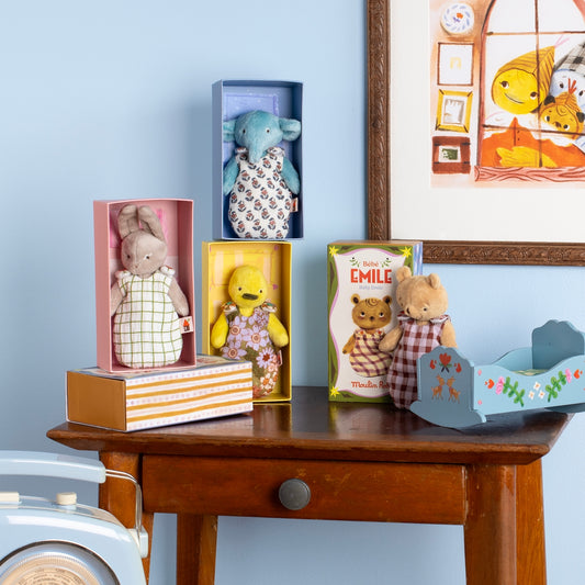 Moulin Roty baby plush toys collection on wooden table with cradle