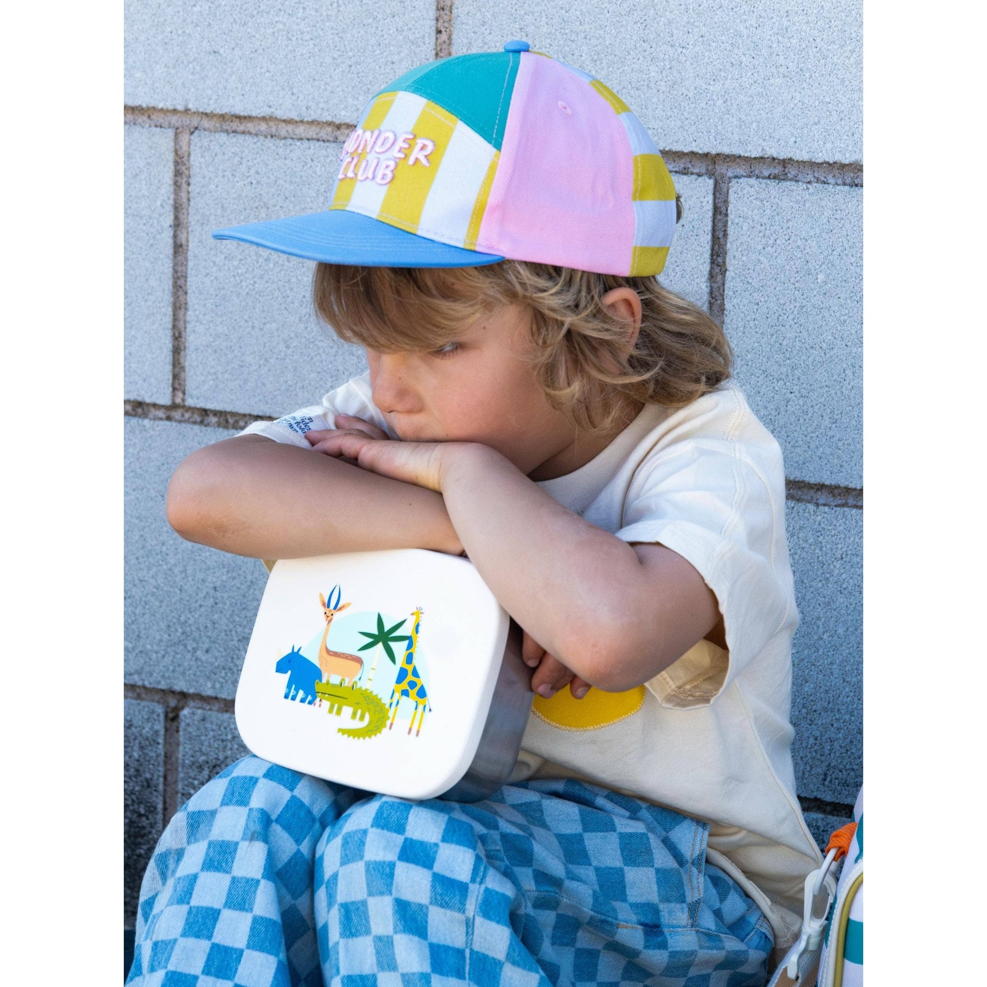 Child holding stainless steel lunchbox with jungle animal design against wall