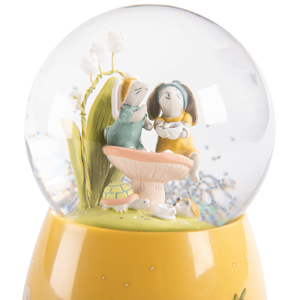 Close-up of rabbit figurines on mushroom inside musical snow globe