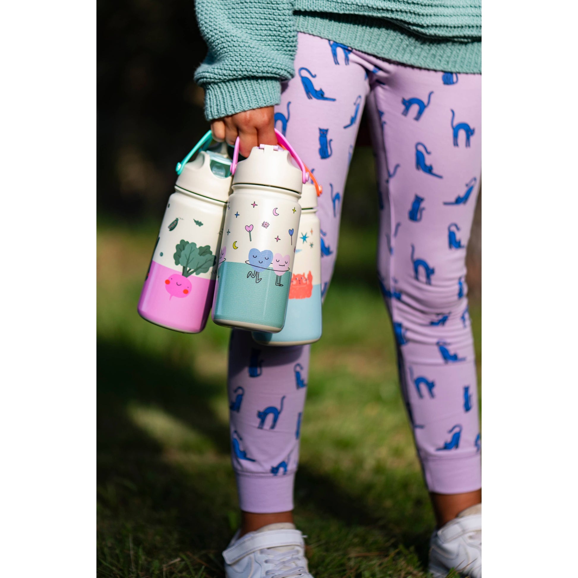 Child holding pastel colored kids bottles with stars and moons