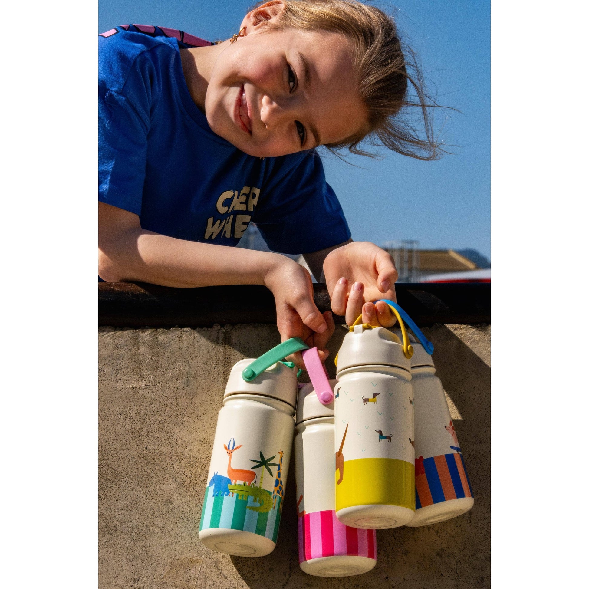 Four kids insulated bottles with giraffe, dachshund, and striped patterns held by child