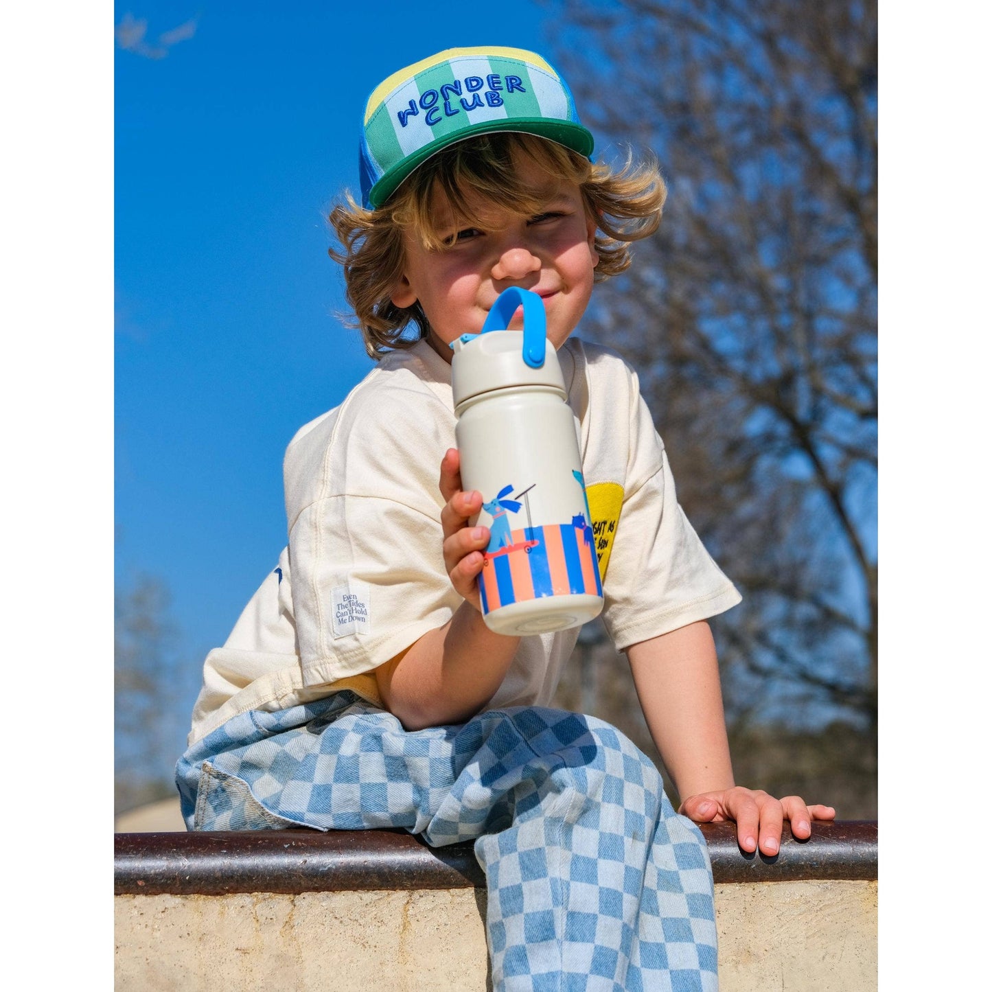 Child drinking from white bottle with bird scooter graphic and blue handle