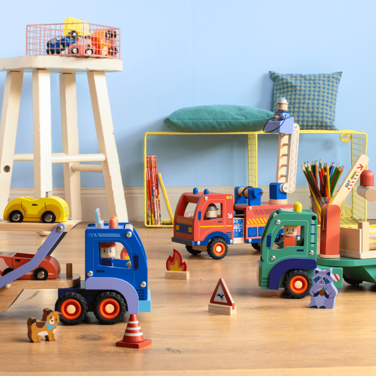 Wooden toy fire truck playset with ladder, accessories, and tow truck on floor