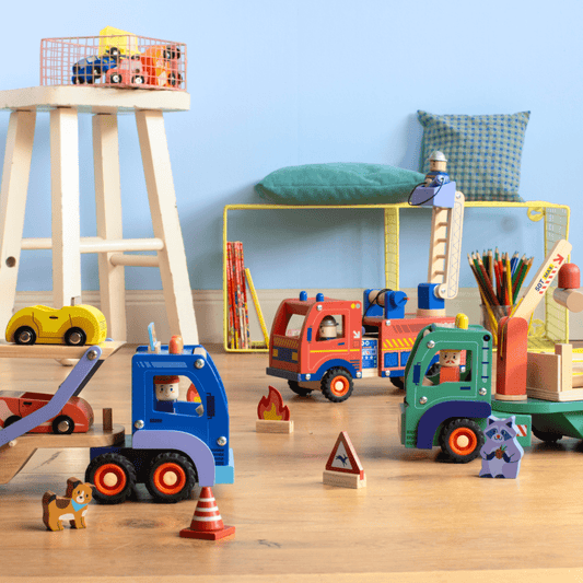 Wooden toy fire truck playset with ladder, accessories, and tow truck on floor