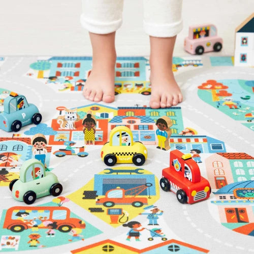 Wooden toy vehicles on illustrated town play mat with child feet