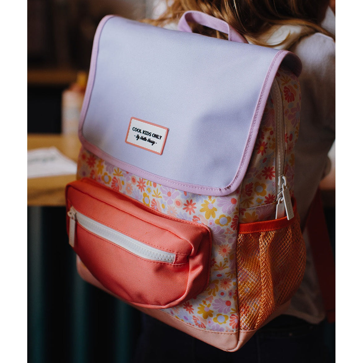 Child wearing pastel floral Hello Hossy backpack with coral pocket