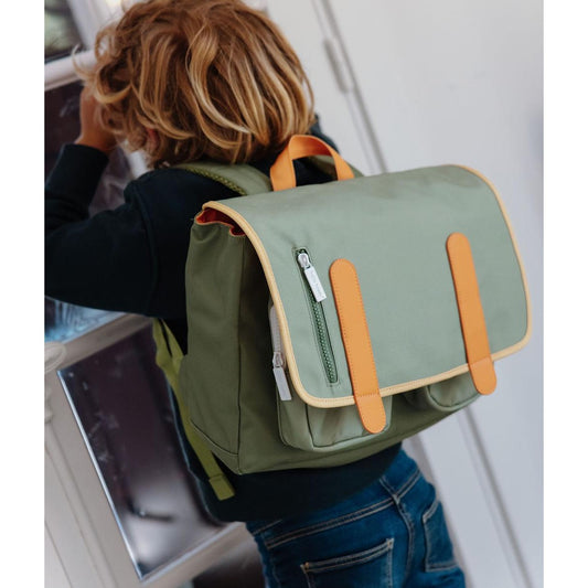 Child wearing olive green backpack with tan flap accents and zippered pocket