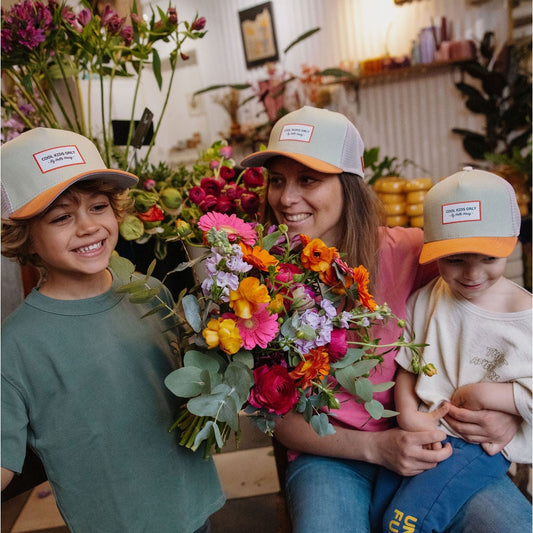 Family wearing matching green and orange kids trucker caps in floral shop