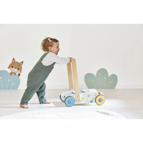 Barefoot toddler pushing Janod wooden walker with forest decals