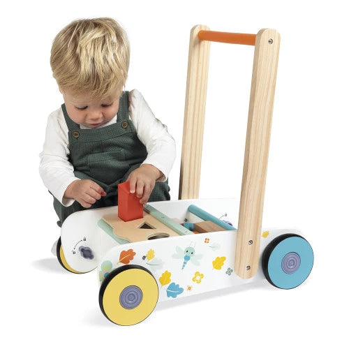 Toddler using Janod wooden push walker shape sorter activity