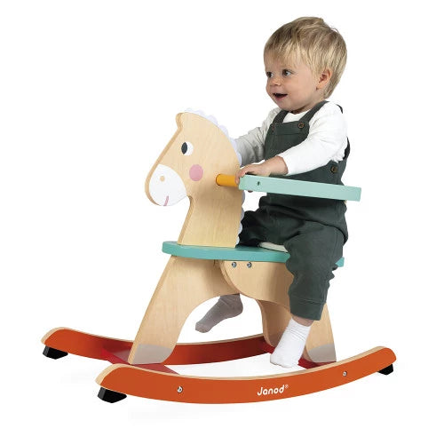 Child sitting on Janod natural wood rocking horse