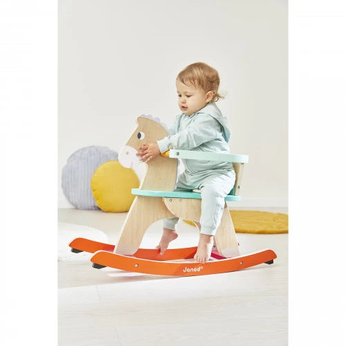 Toddler playing with Janod wooden rocking horse indoors