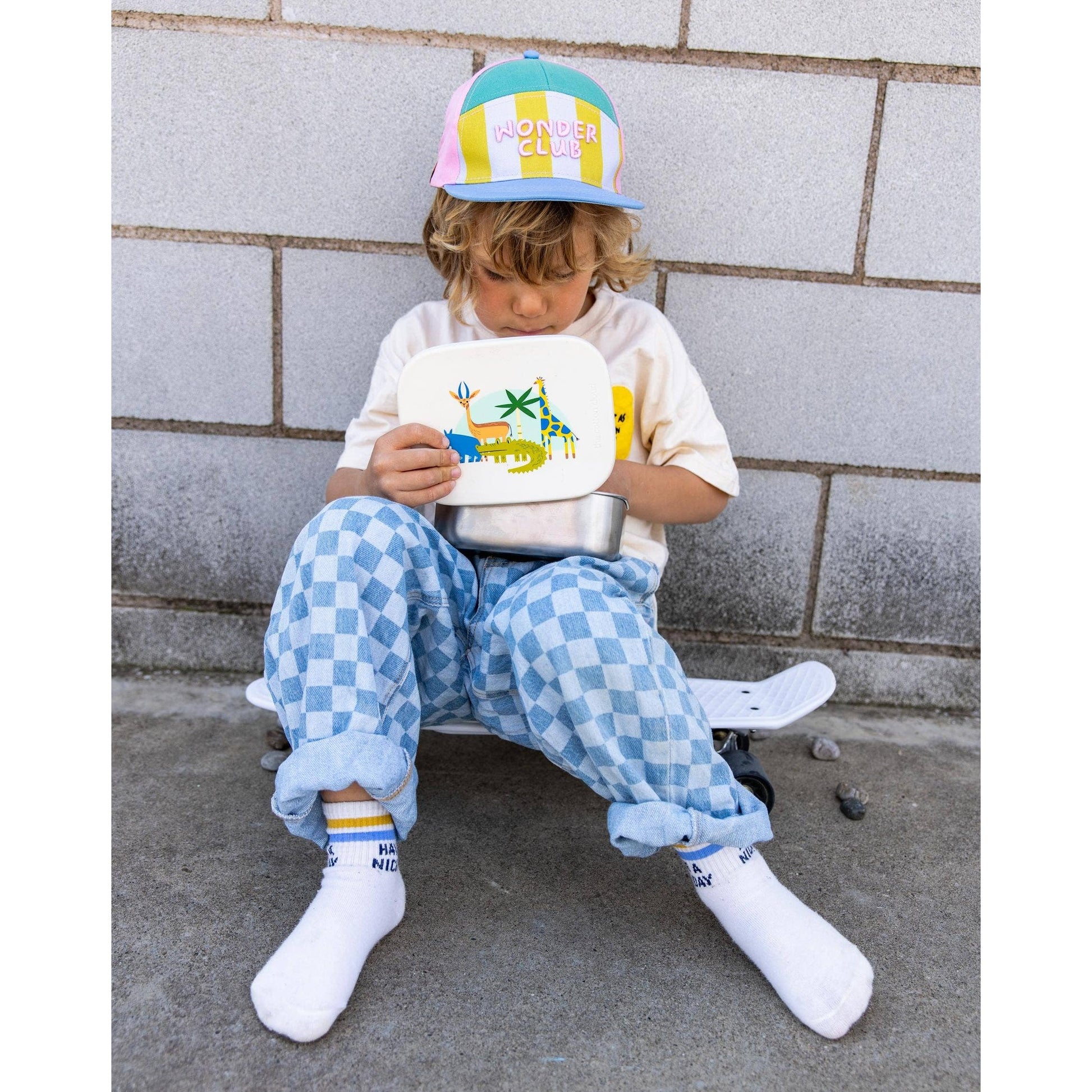 Child holding white stainless steel lunchbox with animal print lid