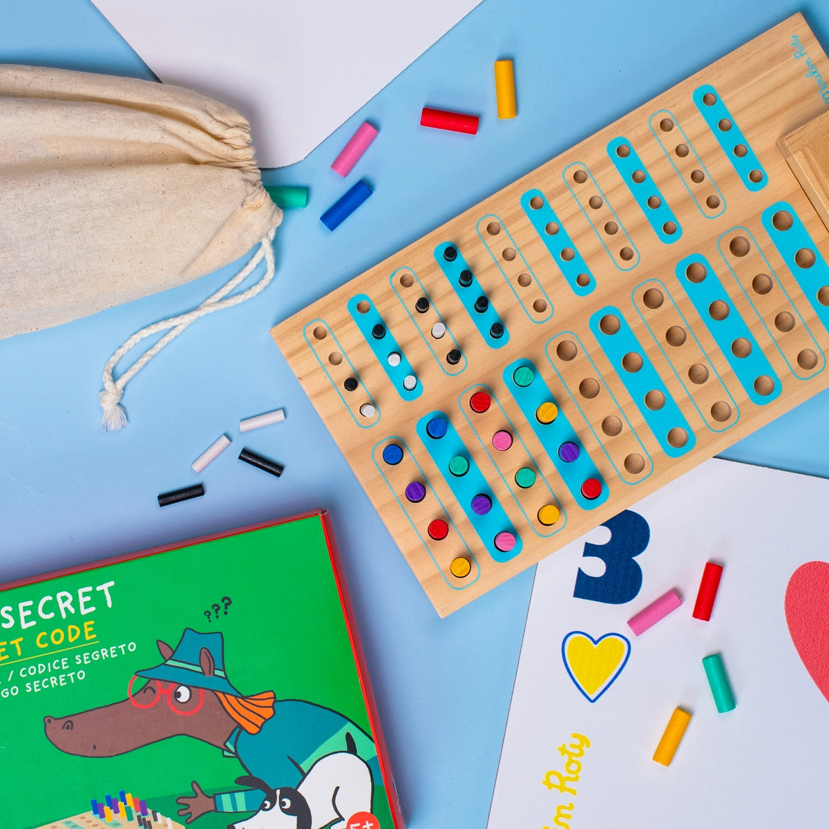 Flat lay of Code Secret wooden board game with scattered colored pegs