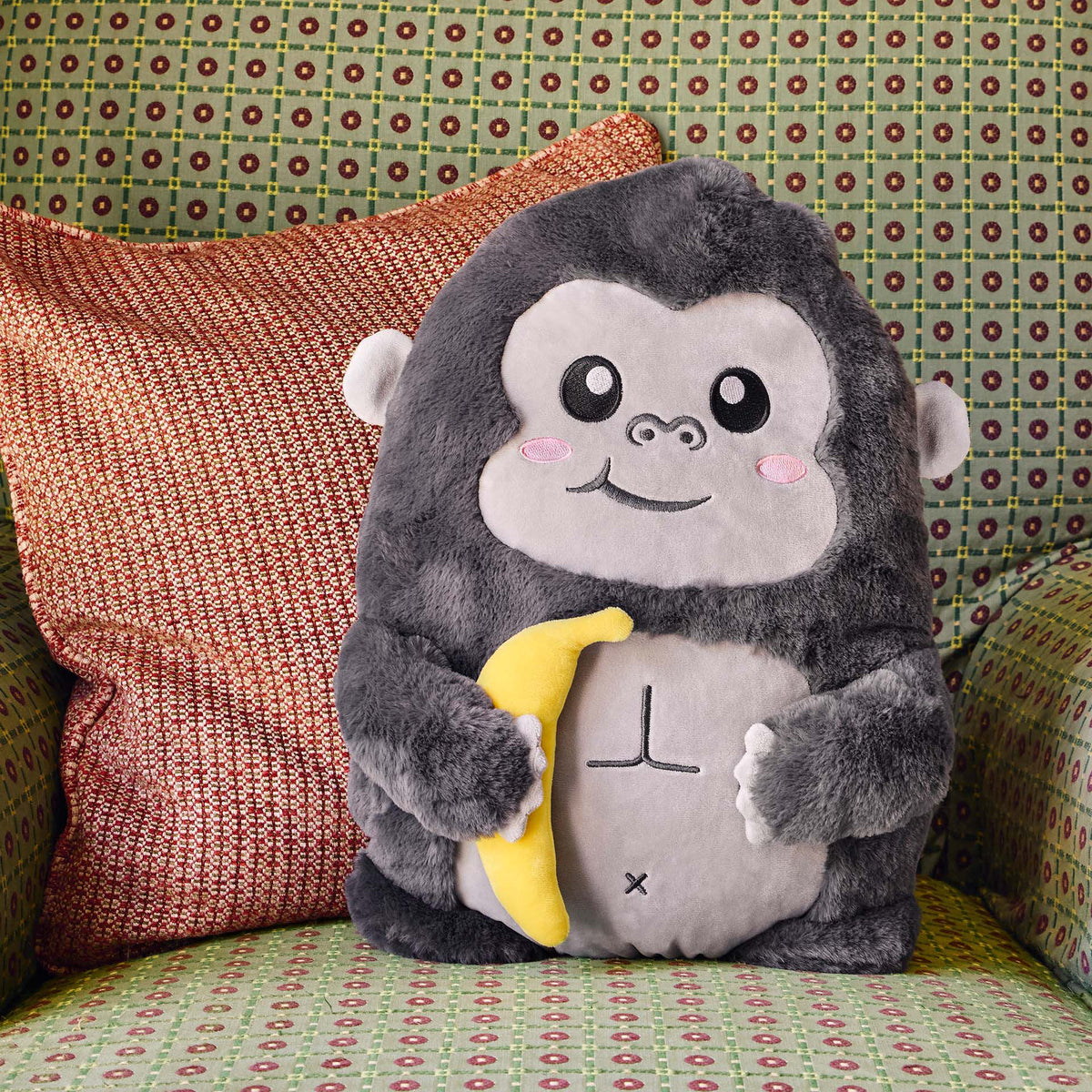 Grey gorilla cushion styled on patterned sofa with throw pillow