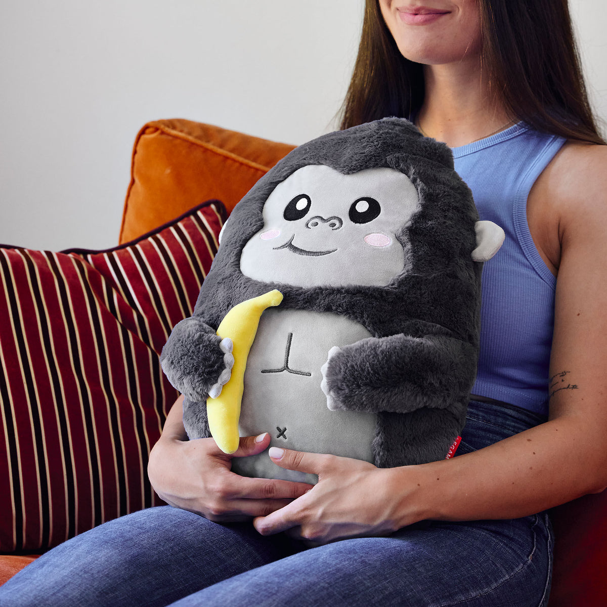 Person hugging large soft grey gorilla pillow on lap