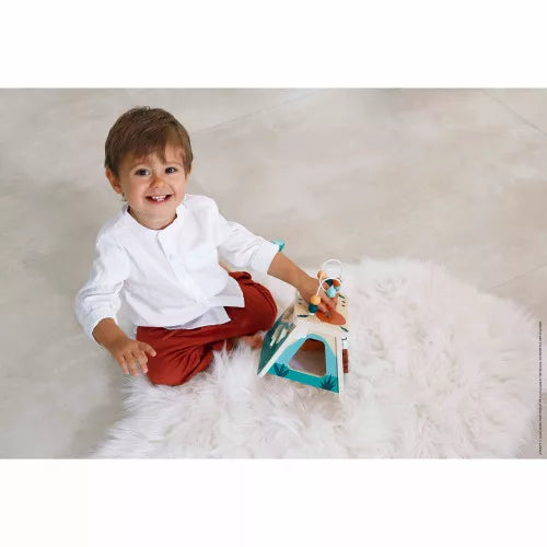 Toddler playing with Janod wooden volcano activity cube on rug