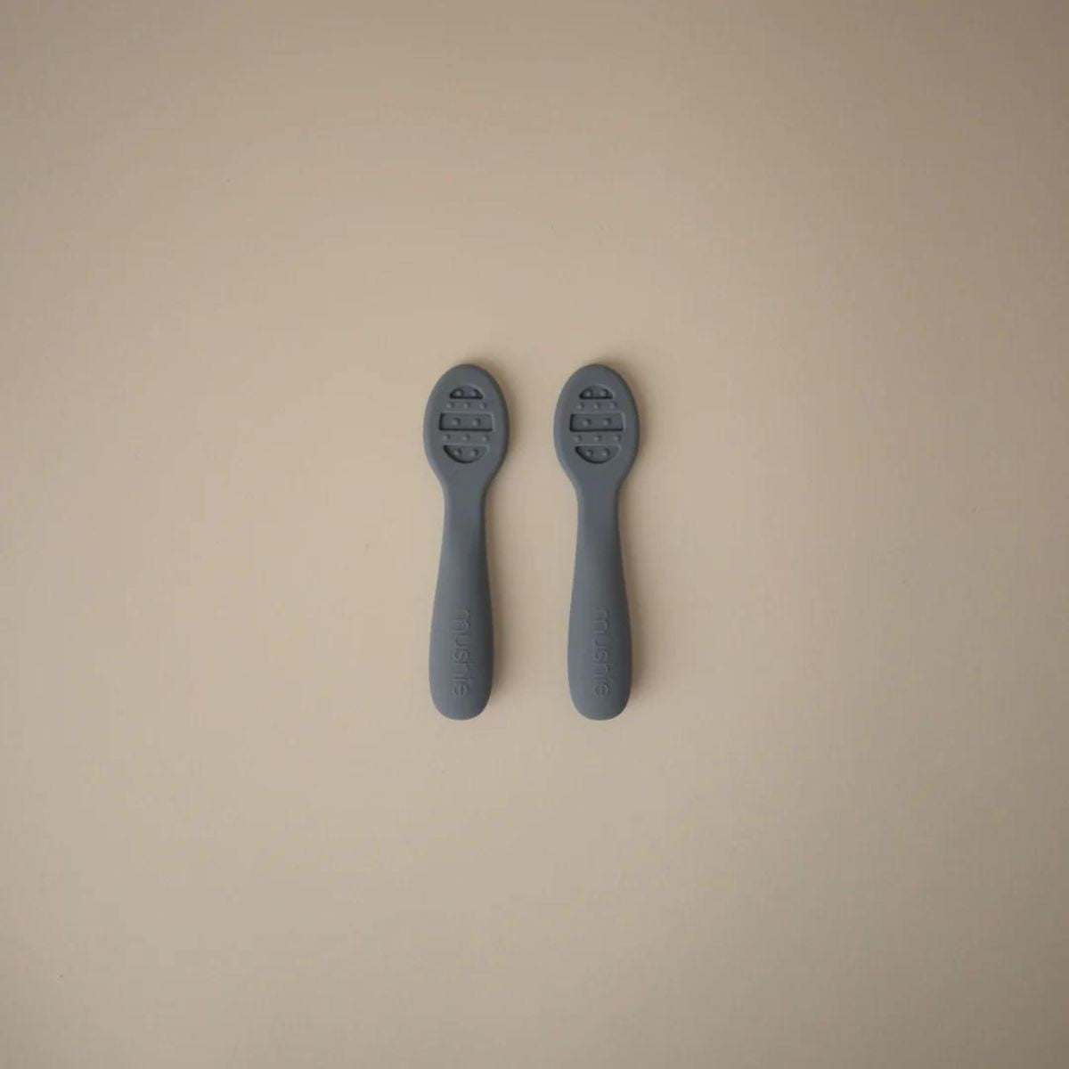 Close-up of textured bowl design on slate blue Mushie baby spoon