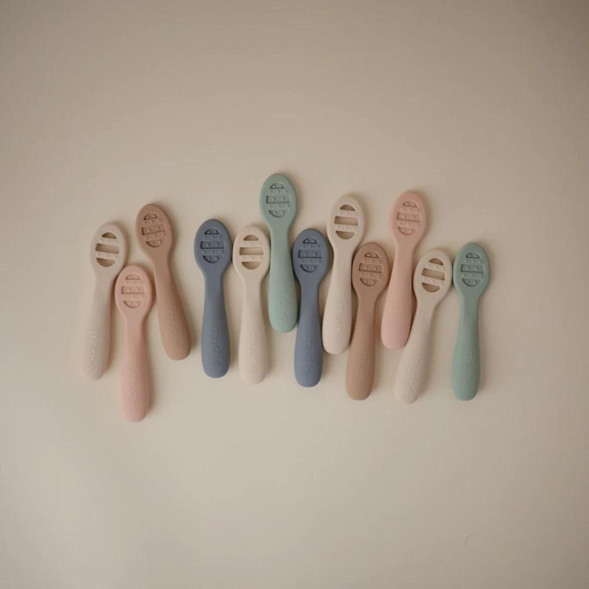 Assorted earthy tone Mushie silicone baby feeding spoons collection