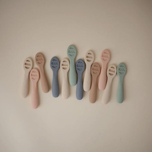 Assorted earthy tone Mushie silicone baby feeding spoons collection