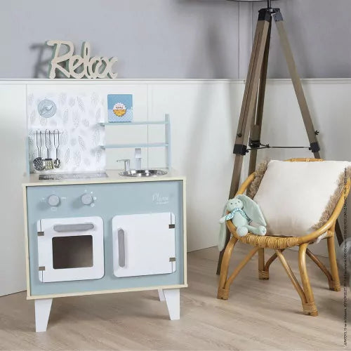 Wooden play kitchen in nursery setting with white wainscoting and decor