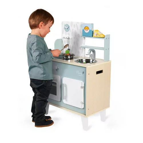 Boy cooking with wooden play kitchen including metal pot and utensils
