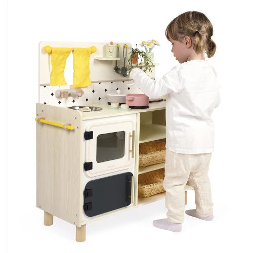 Child reaching for pink pot on Mamie Soleil wooden kitchen with wicker baskets