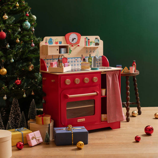 Red wooden play kitchen with lights and sounds in holiday setting