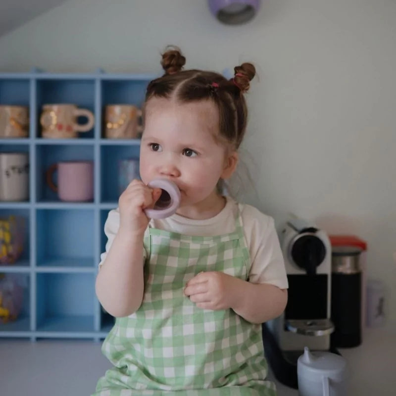 Toddler using soft lilac silicone baby food feeder for safe self-feeding