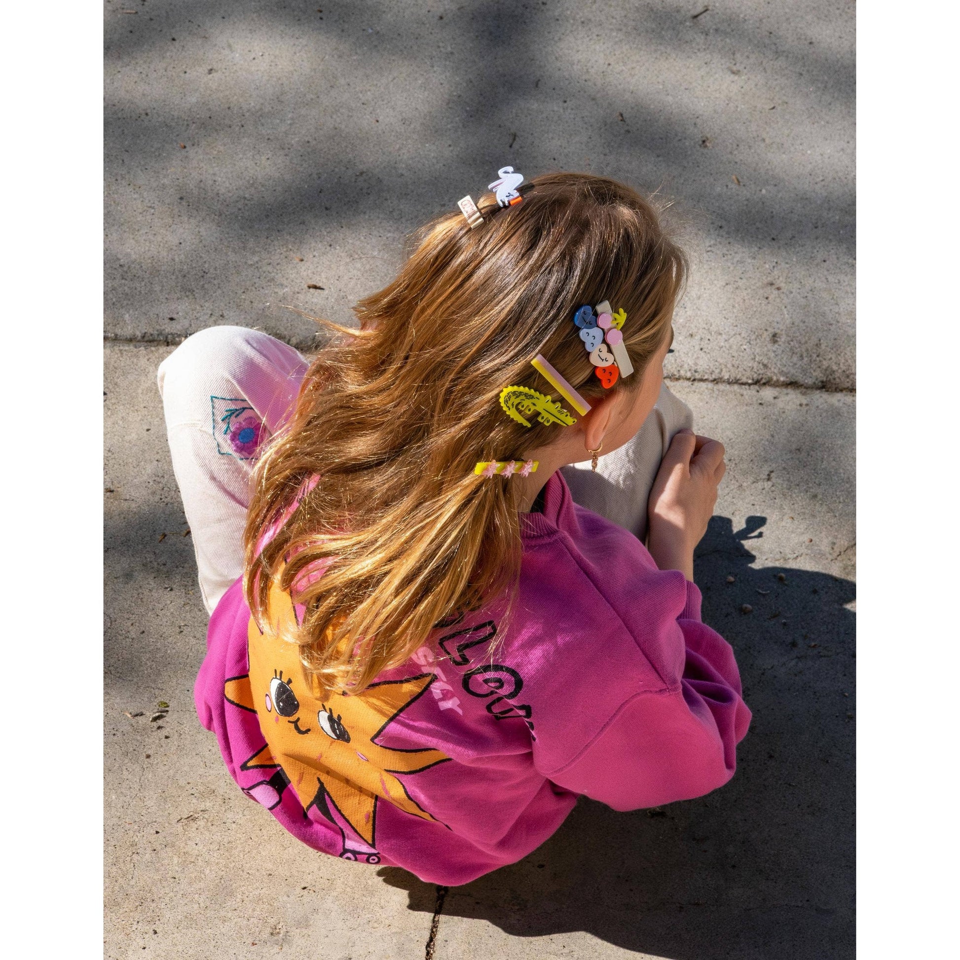 Child back view showing swan and smiley face hair clips in sunlight