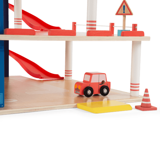 Close-up of wooden toy car and traffic cone accessories on the ground level of the garage set