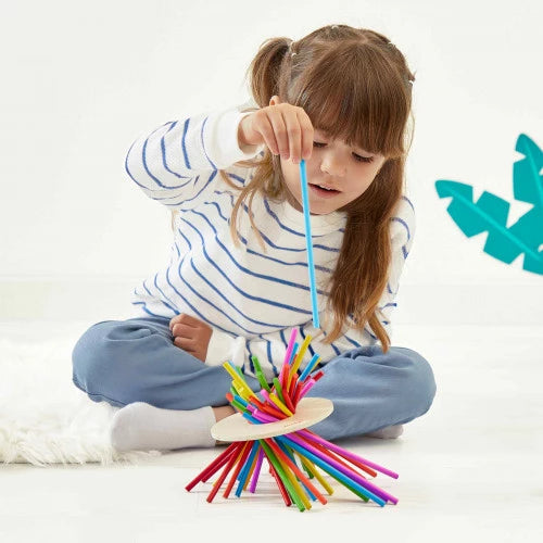 Young girl playing JANOD Crazy Sticks balance game pulling blue stick