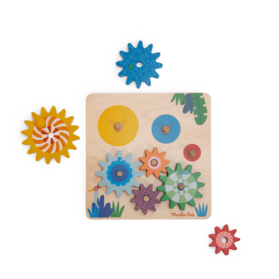 Partially assembled Moulin Roty wooden gear game board with loose colorful cogs on white background