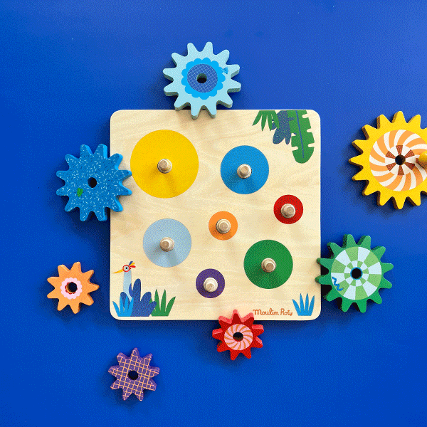 Flat lay of empty Moulin Roty wooden gear board and seven loose colorful wooden gears