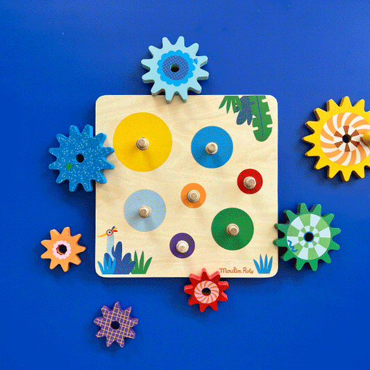 Flat lay of empty Moulin Roty wooden gear board and seven loose colorful wooden gears