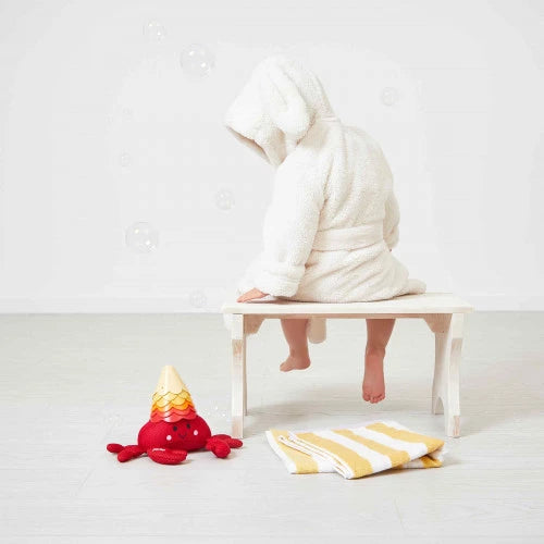 Toddler in bathrobe playing with stacked cup crab toy during bath time