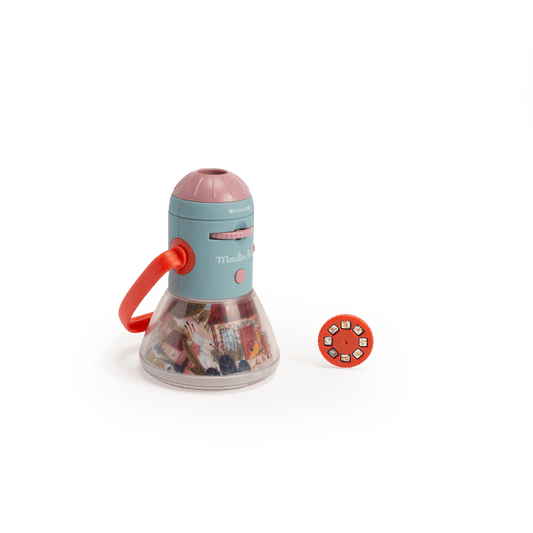 Teal and pink Moulin Roty story lantern next to orange projection disc on white background