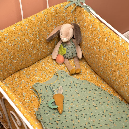 Plush rabbit toy in crib with matching sage green sleep sack