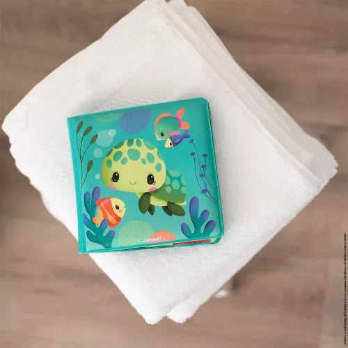 Closed square Janod bath book on towel with smiling green sea turtle cover