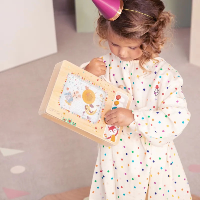 Toddler holding Lilliputiens animated wooden music box toy with fabric handle