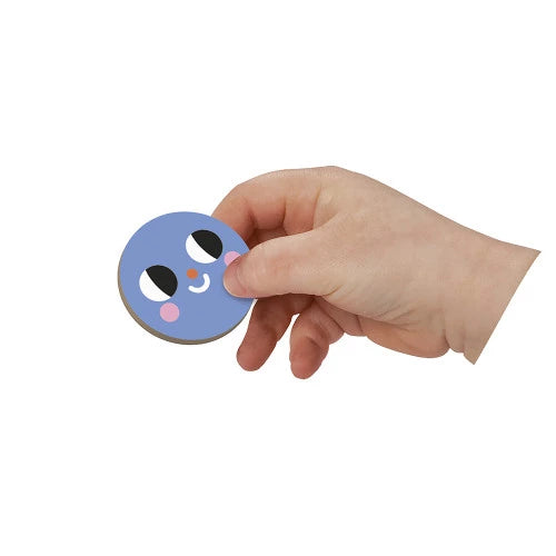 Close-up of child hand holding blue round magnetic piece with cartoon face from JANOD set